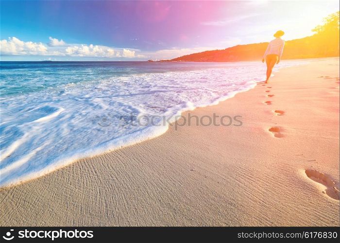 Woman at beautiful beach at Seychelles walking on sand. Focus on footprints.