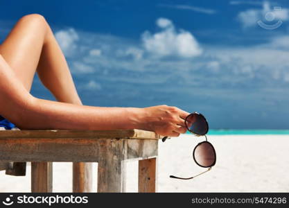 Woman at beautiful beach holding sunglasses