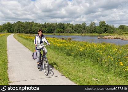 Woman at bike in Dutch national park with forest and wetlands. Biking woman in Dutch national park with forest and wetlands