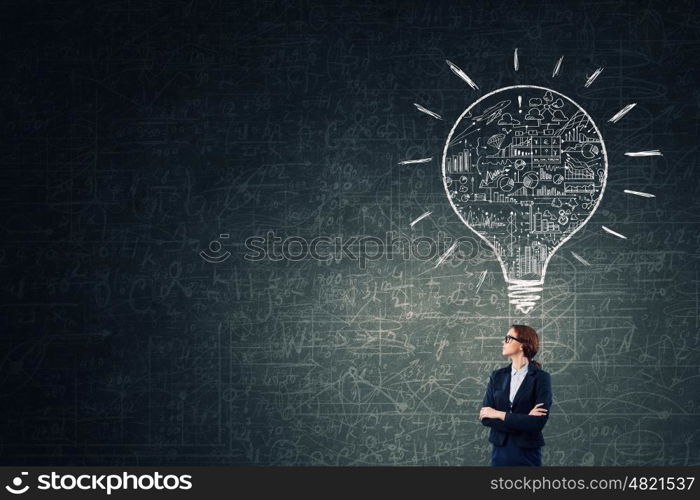 Woman at blackboard. Young confident woman wearing glasses standing near blackboard