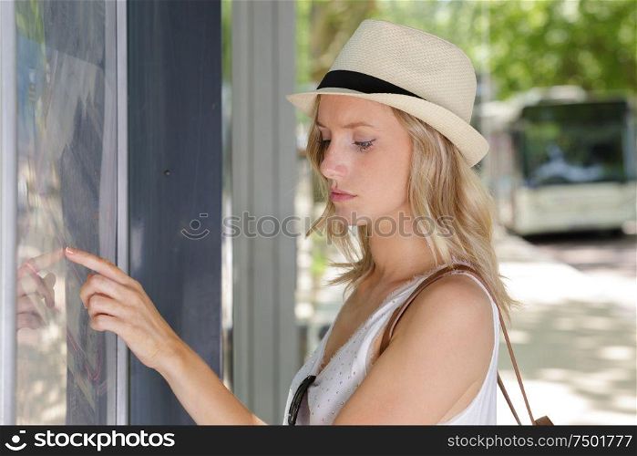 woman at bus stop reading timetable