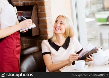 Woman at cafe. Young attractive woman making order at restaurant