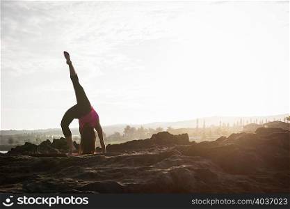 Woman at coast practicing upside down yoga pose, Hawea Point, Maui, Hawaii, USA