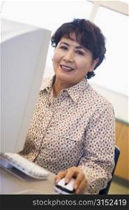 Woman at computer smiling and looking at monitor (high key)