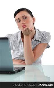 Woman at desk blowing kiss