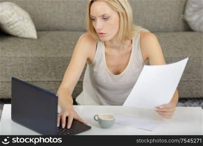 woman at home holding letter and using laptop