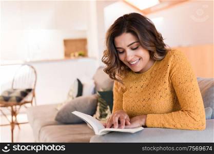 Woman At Home Lying On Reading Book on sofa