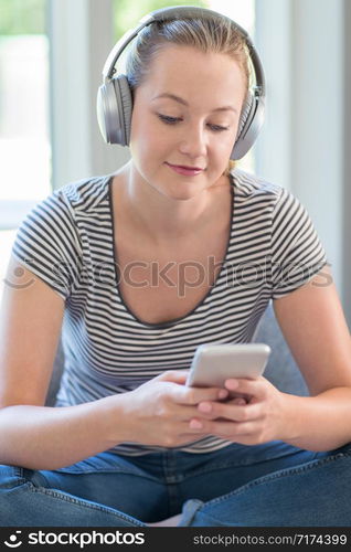 Woman At Home Streams Music From Mobile Phone To Wireless Headphones