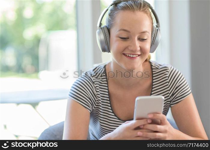 Woman At Home Streams Music From Mobile Phone To Wireless Headphones