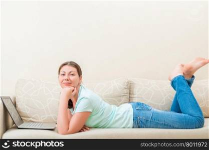 Woman at home working in the internet while lying on the couch
