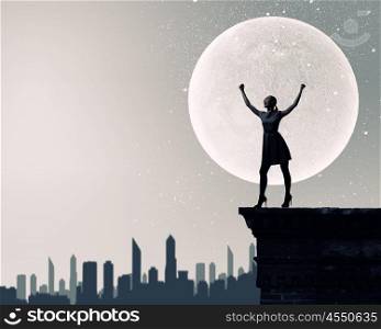 Woman at night. Silhouette of woman against full moon with hands up