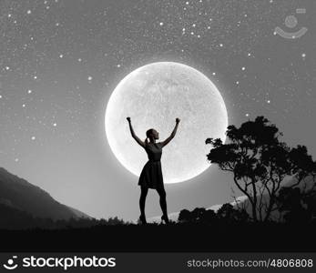 Woman at night. Silhouette of woman against full moon with hands up