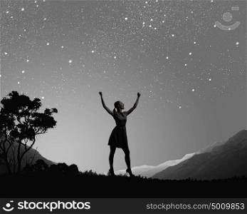 Woman at night. Silhouette of woman in dress at night with hands up