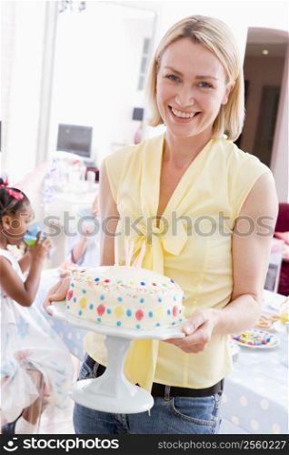Woman at party holding birthday cake smiling