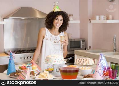 Woman at party holding drink standing by food table smiling