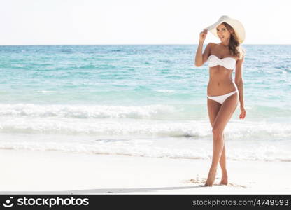 Woman at sea beach. Beautiful young woman in sexy bikini standing at sea beach