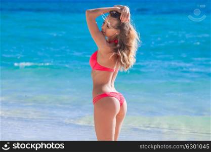 Woman at sea beach. Beautiful young woman in sexy bikini standing at sea beach