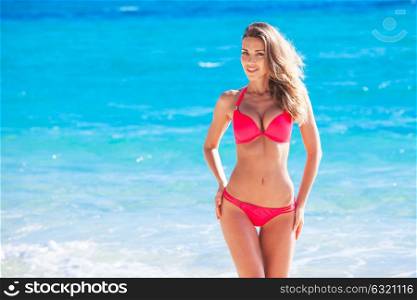 Woman at sea beach. Beautiful young woman in sexy bikini standing at sea beach