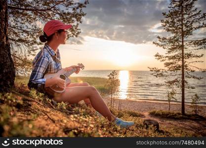 Woman at sunset playing the ukulele
