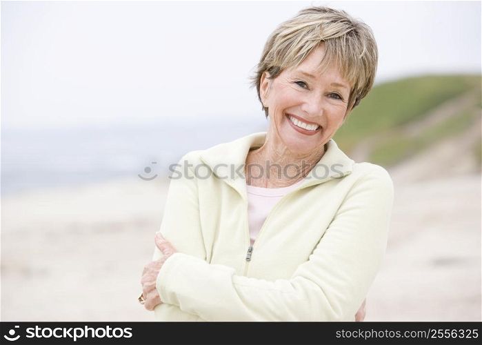 Woman at the beach with arms crossed smiling