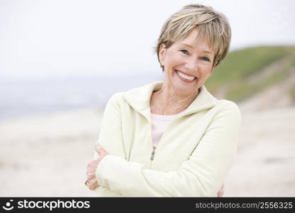 Woman at the beach with arms crossed smiling