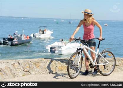 woman at the coast with her bicycle admiring the view