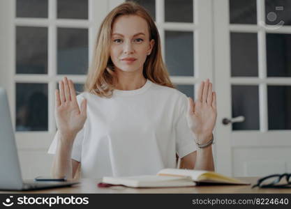 Woman at the desk gestures stop. Successful mid adult businesswoman is working from home in evening. Lovely european lady is freelancer, manager, executive or accountant. Stop stress and overworking.. Woman at the desk gestures stop. Concept of stopping stress and overworking in evening.