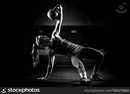 Woman athlete exercising with kettlebell indoors