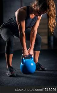Woman athlete exercising with kettlebell indoors