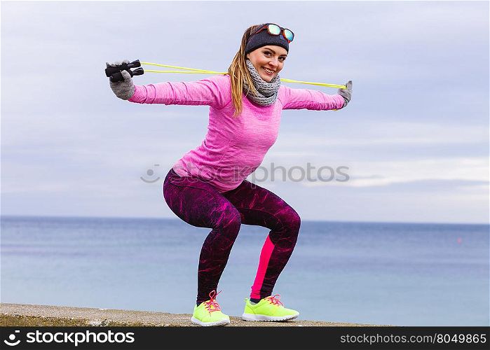 Woman athlete fit girl training outdoor with jumping skipping rope wearing warm sporty clothes in cold day. Sports activity in winter or autumn time, healthy lifestyle concept