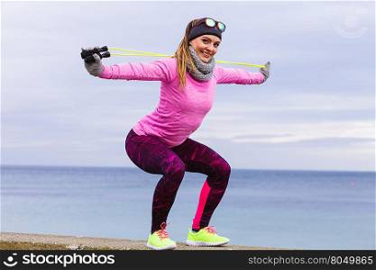 Woman athlete fit girl training outdoor with jumping skipping rope wearing warm sporty clothes in cold day. Sports activity in winter or autumn time, healthy lifestyle concept