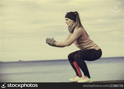Woman athlete girl training wearing warm sporty clothes outside by seaside in cold weather. Sports and activities in winter or autumn time.. Woman fitness sport girl training outdoor in cold weather