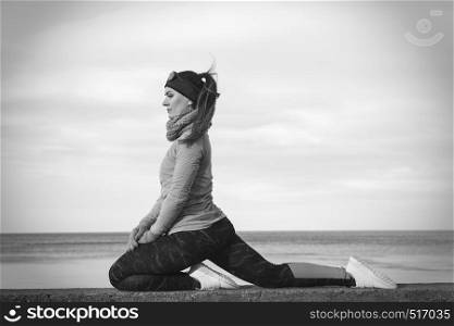 Woman athlete girl training wearing warm sporty clothes outside by seaside in cold weather. Sports and activities in winter or autumn time.. Woman fitness sport girl training outdoor in cold weather