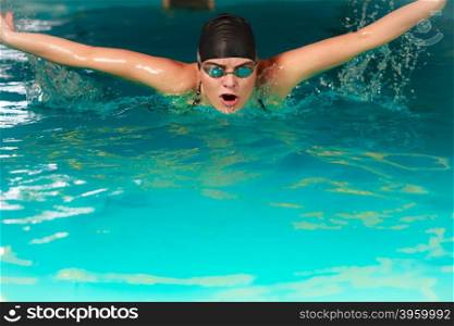 Woman athlete swimming butterfly stroke in pool.. Woman athlete swimming performing butterfly style stroke in pool. Active human swimmer taking breath. Water sport comptetition.