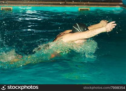 Woman athlete swimming butterfly stroke in pool.. Woman athlete swimming performing butterfly style stroke in pool. Active human swimmer taking breath. Water sport comptetition.