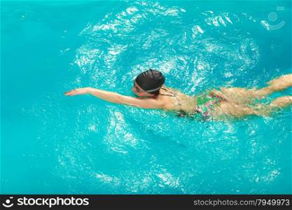 Woman athlete swimming crawl stroke in pool.. Woman athlete swimming performing crawl style stroke in pool. Active human swimmer taking breath. Water sport comptetition.