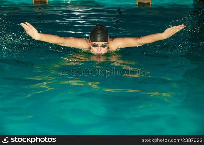 Woman athlete swimming in pool. Active human swimmer taking breath. Water sport comptetition.. Woman athlete swimming in pool.