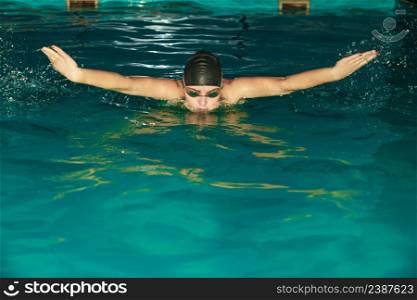 Woman athlete swimming in pool. Active human swimmer taking breath. Water sport comptetition.. Woman athlete swimming in pool.
