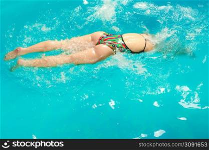 Woman athlete swimming performing crawl style stroke in pool. Active human swimmer taking breath. Water sport comptetition.. Woman athlete swimming crawl stroke in pool.