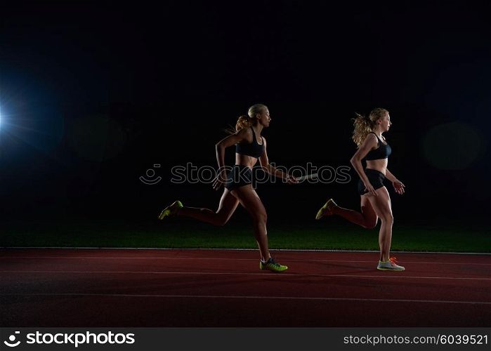 woman athletic runners passing baton in relay race
