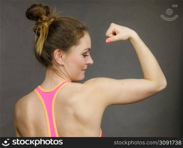 Woman athletic young girl showing muscles of the back and shoulders on black background. Beauty fit female body. Woman showing muscles of the back and shoulders