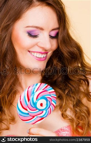 Woman attractive cheerful girl colorful make up holding big lollipop candy in hand. Sweet food and enjoying concept. Studio shot bright background. Woman holding colorful lollipop candy in hand.