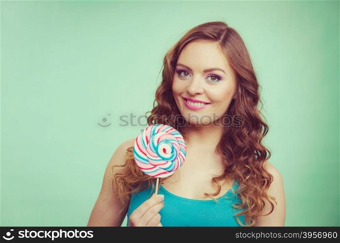 Woman attractive cheerful girl holding colorful lollipop candy in hand. Sweet food and enjoying concept. Studio shot green blue background, toned image