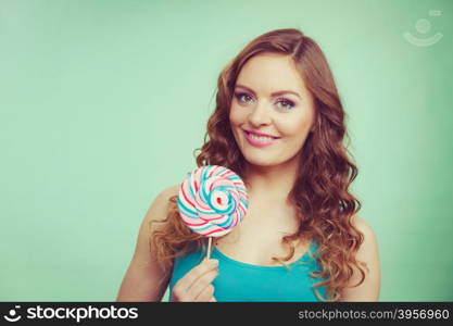 Woman attractive cheerful girl holding colorful lollipop candy in hand. Sweet food and enjoying concept. Studio shot green blue background, toned image