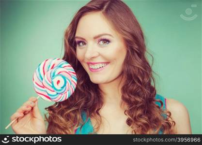 Woman attractive cheerful girl holding colorful lollipop candy in hand. Sweet food and enjoying concept. Studio shot green blue background, toned image