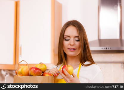 Woman attractive housewife in kitchen with grocery shopping bag, many apple fruits. Healthy eating, cooking, vegetarian food, dieting and people concept.. Woman housewife in kitchen with many fruits