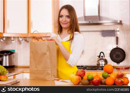 Woman attractive housewife in kitchen with grocery shopping bag, many fruits on counter. Healthy eating, cooking, vegetarian food, dieting and people concept.. Woman housewife in kitchen with many fruits