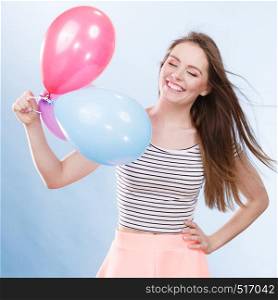 Woman attractive joyful girl playing with colorful balloons. Summer holidays, celebration and lifestyle concept. Studio shot blue background. Woman summer joyful girl with colorful balloons