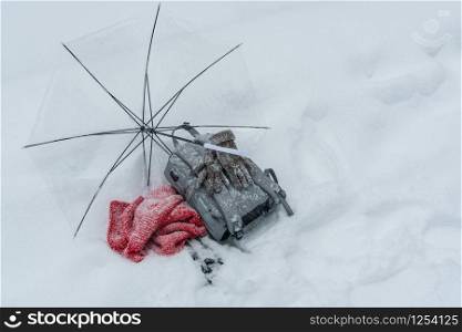 Woman backpack, scarf, winter glove and umbrella on snow.