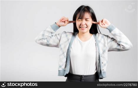 Woman bad mood pain her closed ears with finger and close eyes, Asian beautiful young female covers ears for loud noise, studio shot isolated on white background with copy space
